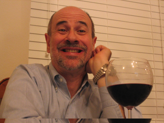 John smiling with glass of wine in foreground
